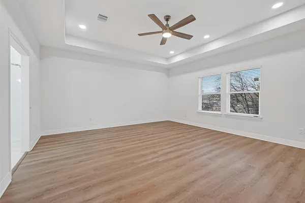 an empty room with wooden floor and windows