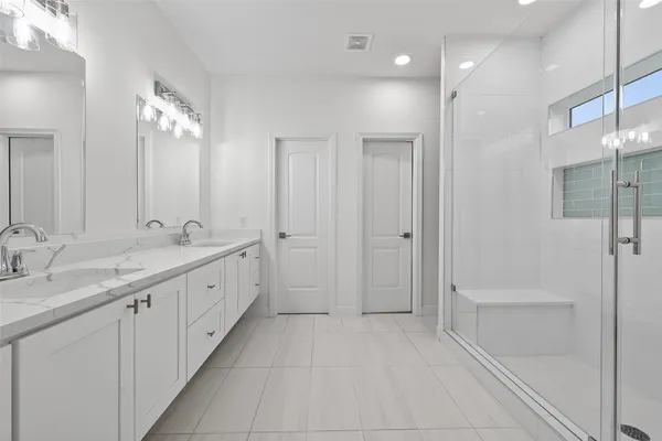 a spacious bathroom with a double vanity sink a large mirror and shower