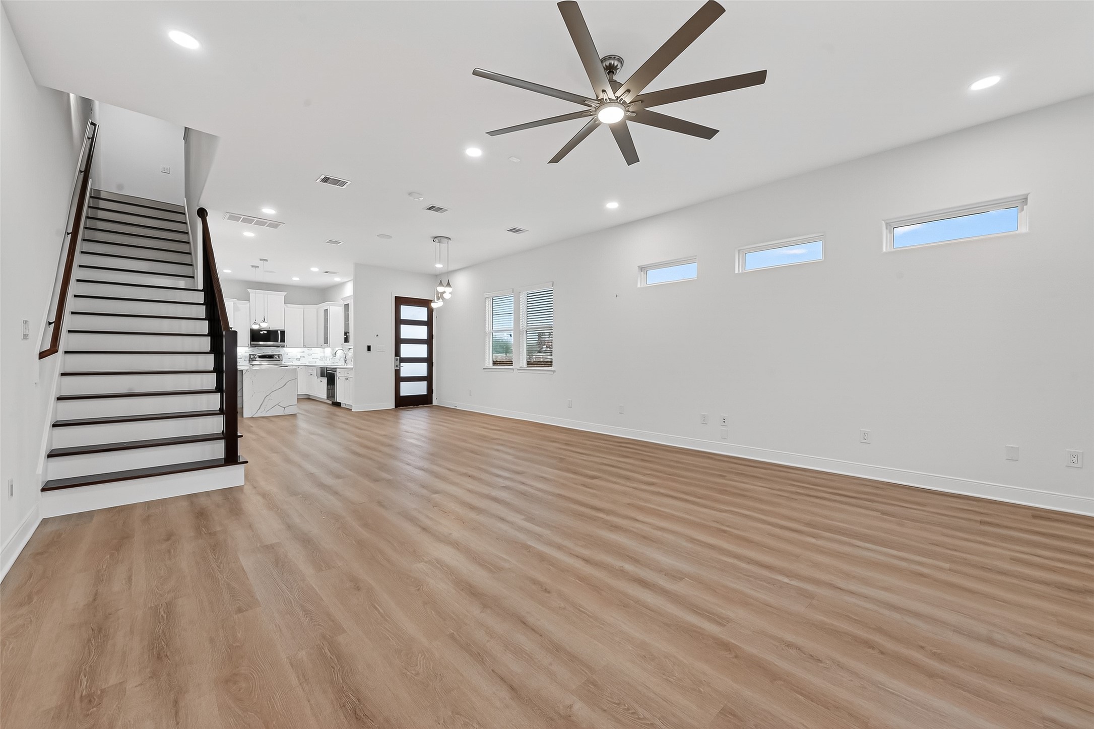 6630 Highrock Road Houston, TX 77092 - Photo 7 of 40 an empty room with wooden floor chandelier fan and windows