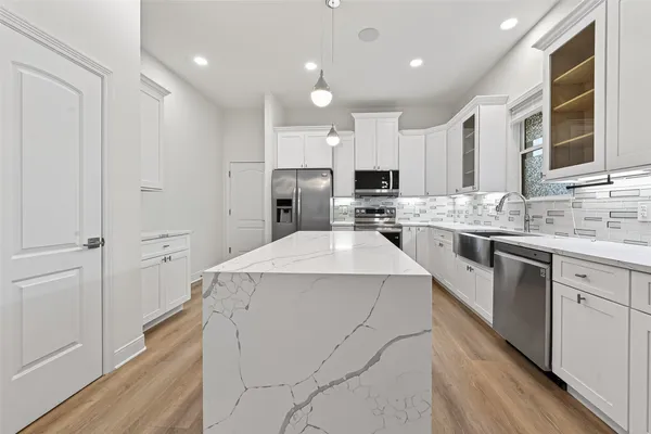 a kitchen that has a lot of white cabinets and stainless steel appliances