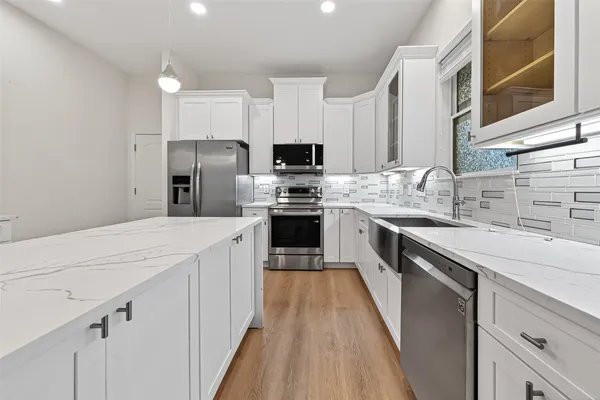 a kitchen with stainless steel appliances granite countertop a white cabinets a sink a stove a refrigerator and white cabinets