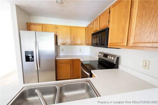 a kitchen with stainless steel appliances wooden cabinets a refrigerator and a sink
