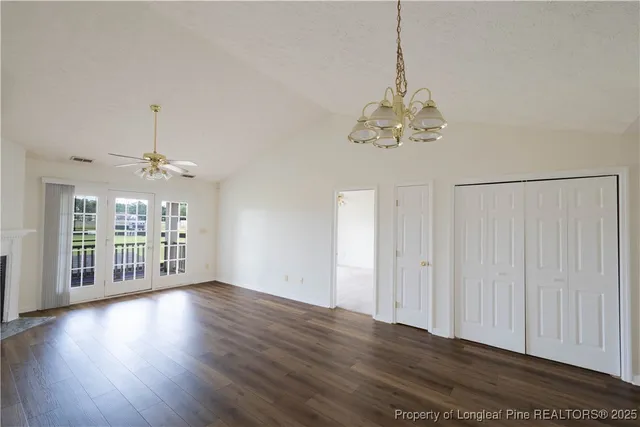 a view of a room with wooden floor chandelier and windows