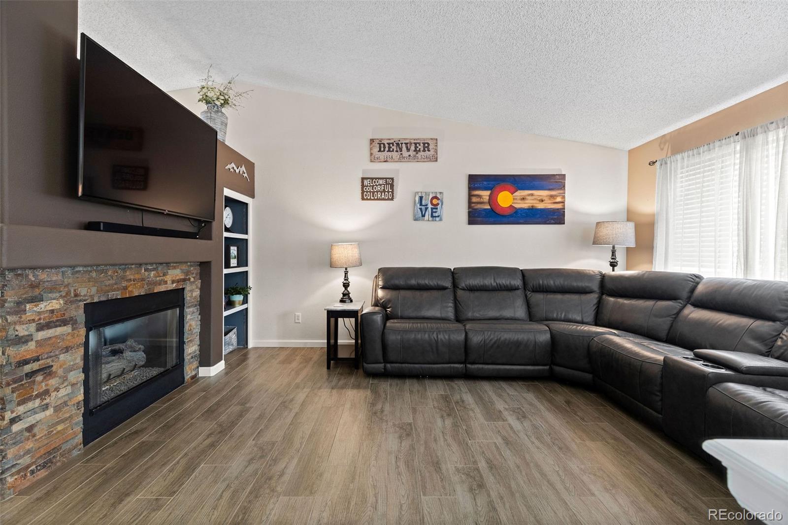 10565 Hyacinth Place Highlands Ranch, CO 80129 - Photo 6 of 33 a living room with furniture a flat screen tv and a fireplace