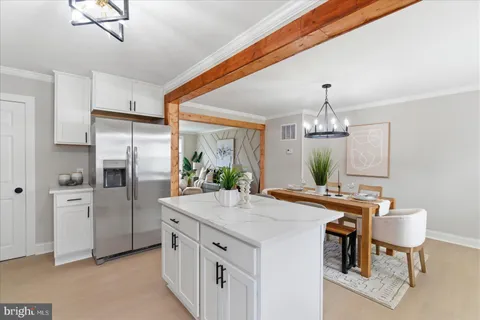 a kitchen with stainless steel appliances a dining table chairs and refrigerator
