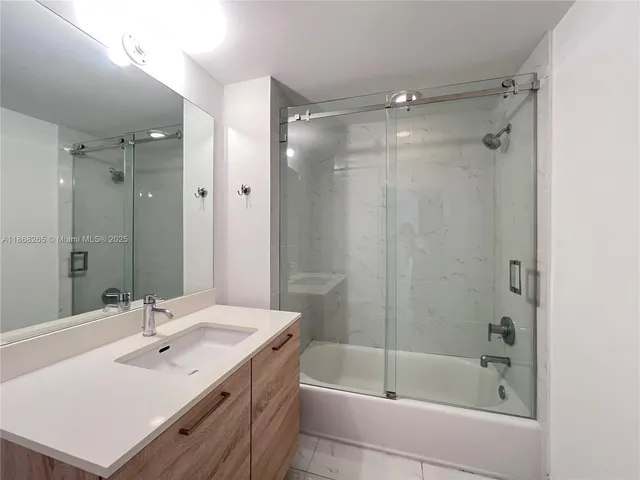 a bathroom with a bath tub sink mirror and shower