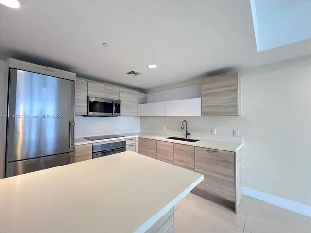 a kitchen with stainless steel appliances a sink a stove a microwave and cabinets