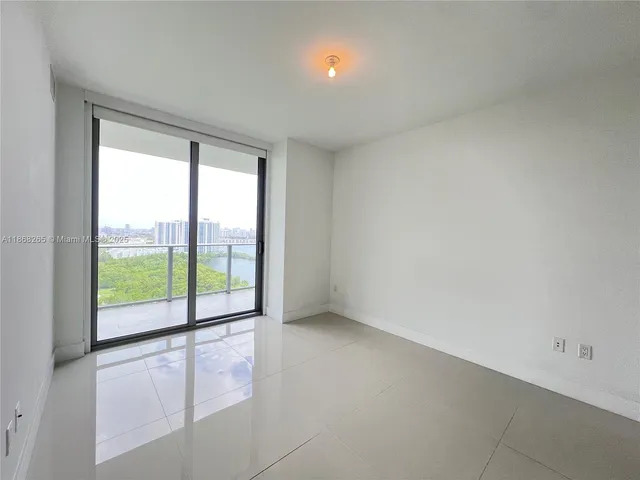 a view of an empty room with wooden floor and windows