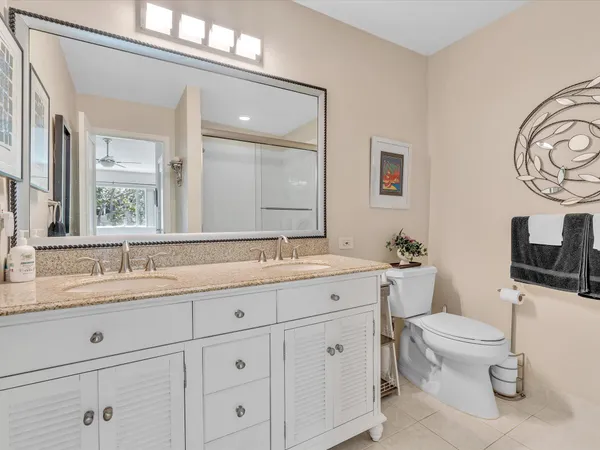 a spacious bathroom with a toilet a double vanity sink and a mirror