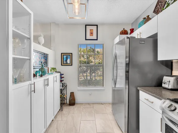 a kitchen with white cabinets and refrigerator