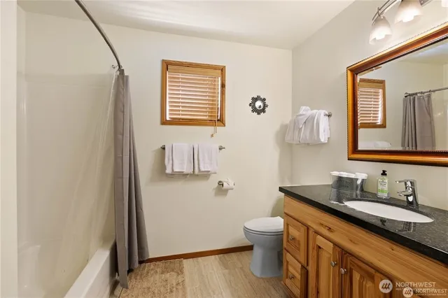 a bathroom with a granite countertop sink toilet and mirror