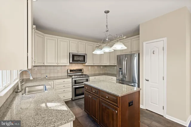 a kitchen with stainless steel appliances granite countertop a sink a counter space and a wooden floors