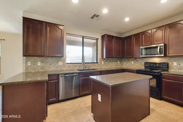 a kitchen with stainless steel appliances granite countertop wooden cabinets a stove a sink and a microwave