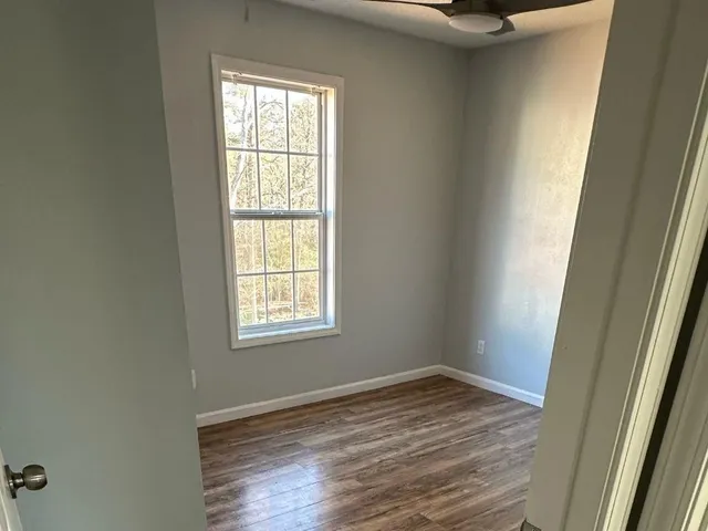 a view of an empty room with wooden floor and a window