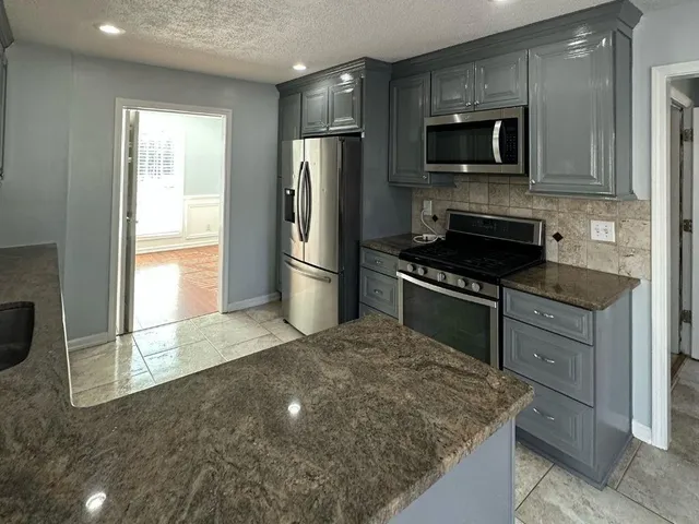a kitchen with kitchen island granite countertop a sink stove and cabinets