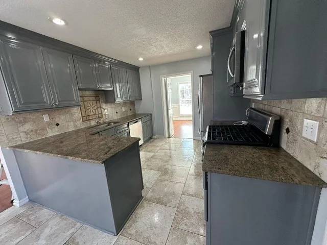a kitchen with stainless steel appliances granite countertop a sink stove and cabinets