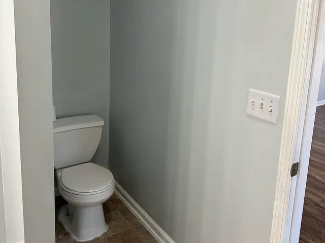 a white toilet sitting next to a white wall