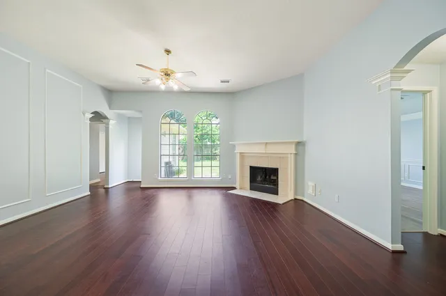 an empty room with wooden floor fireplace and windows