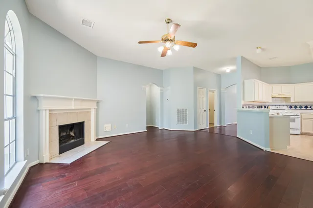 a view of an empty room with wooden floor and a fireplace