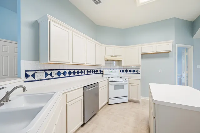 a kitchen with white cabinets sink and white appliances