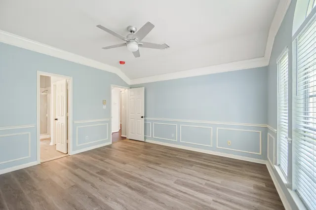 an empty room with wooden floor fan and windows