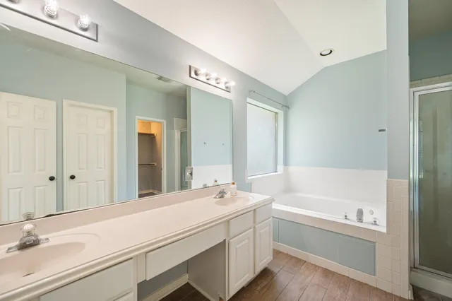 a bathroom with a tub a sink and a large mirror