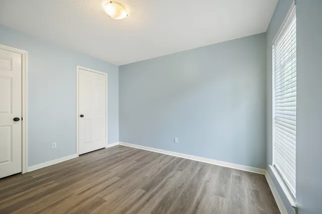a view of an empty room with wooden floor and a window
