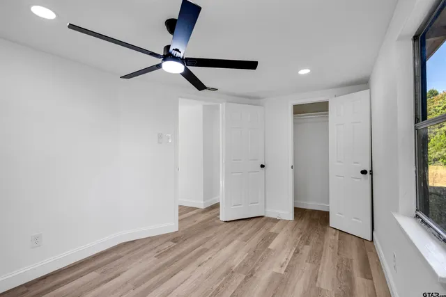 a view of empty room with wooden floor and fan