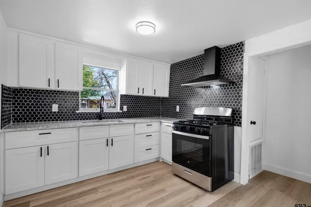 a kitchen with granite countertop white cabinets stainless steel appliances and a sink