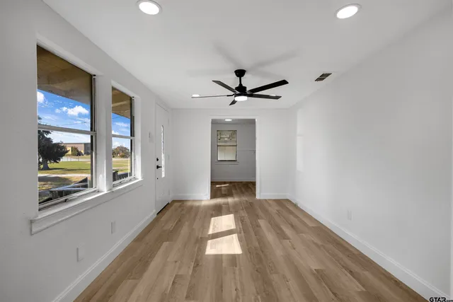 a view of empty room with wooden floor and fan
