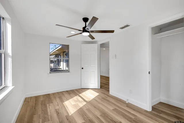 a view of empty room with wooden floor and fan