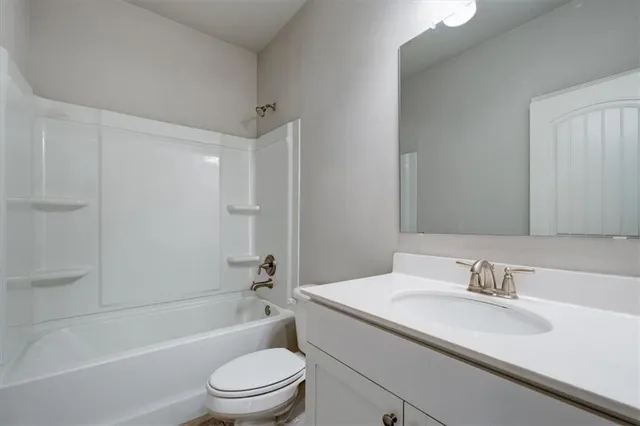 a bathroom with a granite countertop sink a toilet and shower