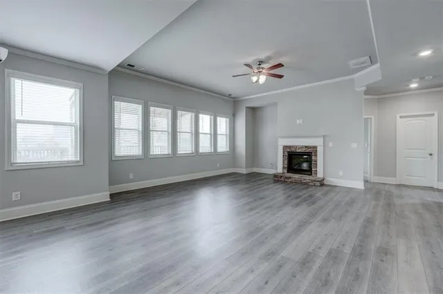 an empty room with windows fireplace and wooden floor