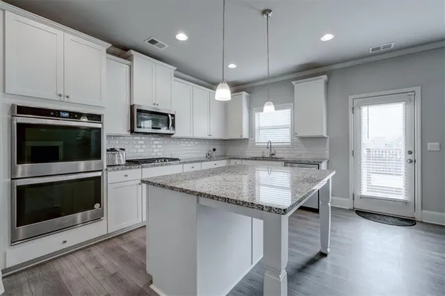 a kitchen with kitchen island granite countertop a stove a sink and a microwave