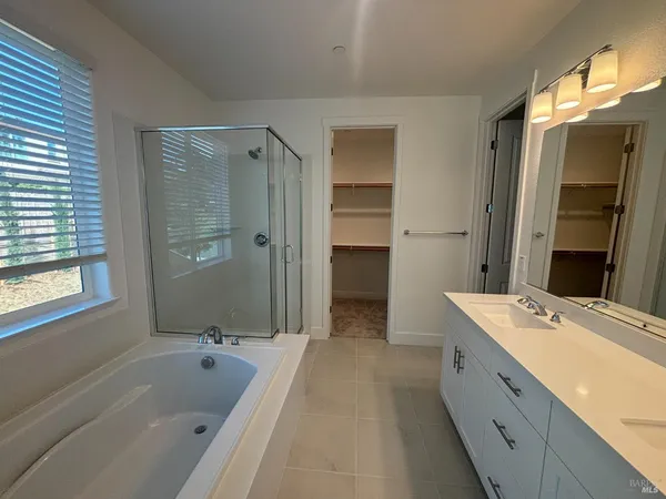 a spacious bathroom with a tub sink shower and mirror