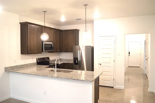 a kitchen with granite countertop a sink a counter space and stainless steel appliances