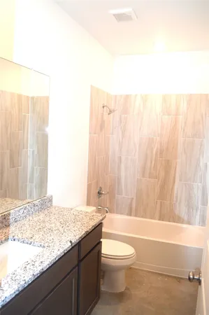 a bathroom with a granite countertop bathtub and toilet