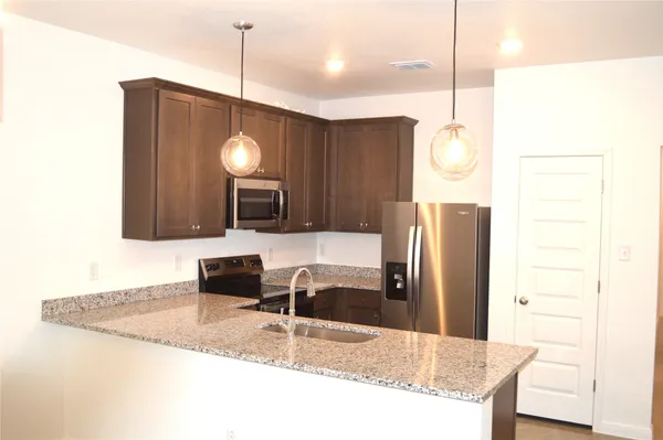 a kitchen with stainless steel appliances granite countertop a sink refrigerator and microwave