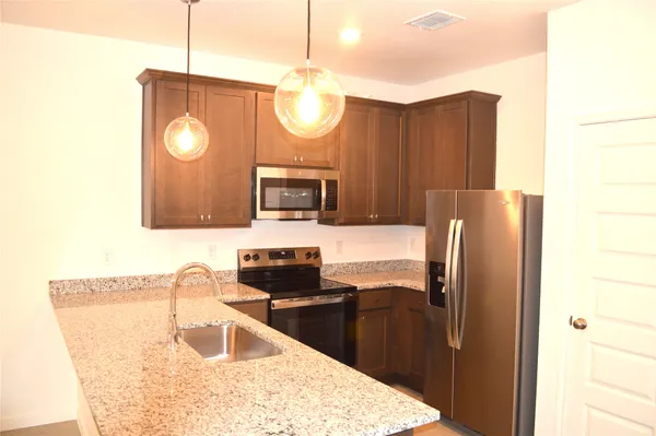 a kitchen with stainless steel appliances granite countertop a refrigerator a stove and a sink