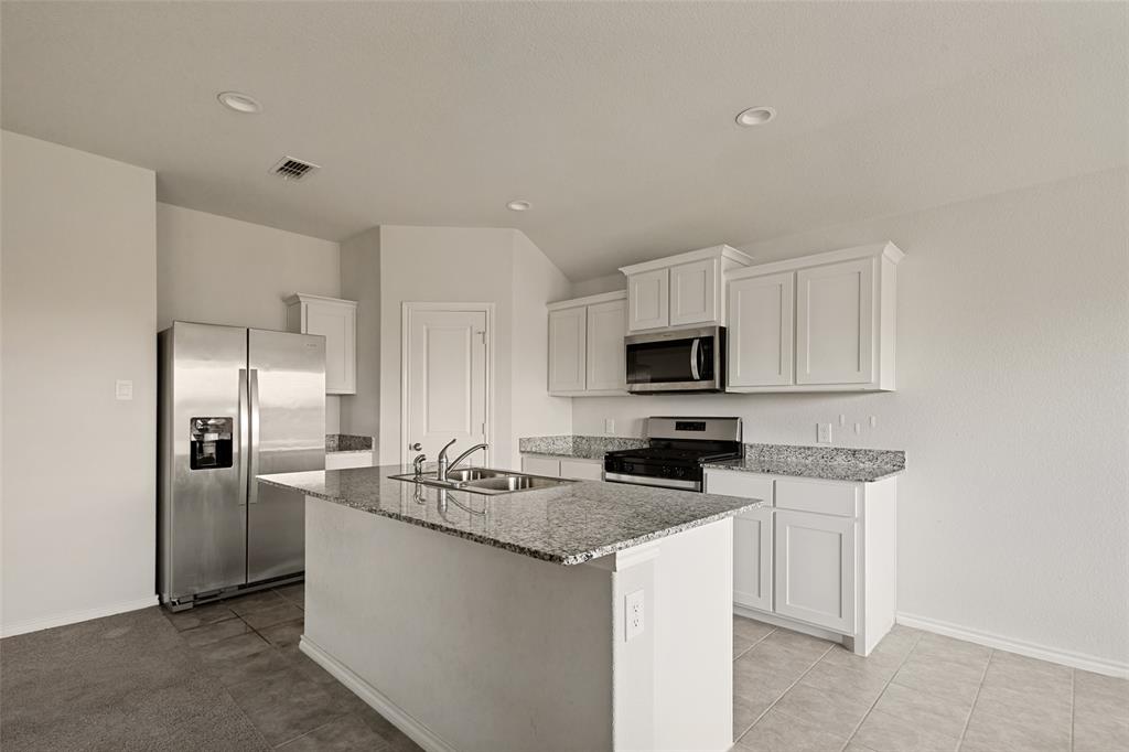 621 Spaulding Street Justin, TX 76247 - Photo 8 of 22 a kitchen with stainless steel appliances granite countertop a sink stove and refrigerator