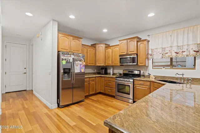 a kitchen with stainless steel appliances granite countertop a refrigerator oven a sink dishwasher and white cabinets with wooden floor