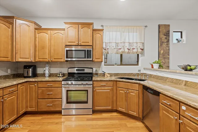 a kitchen with stainless steel appliances granite countertop a stove a sink and a microwave