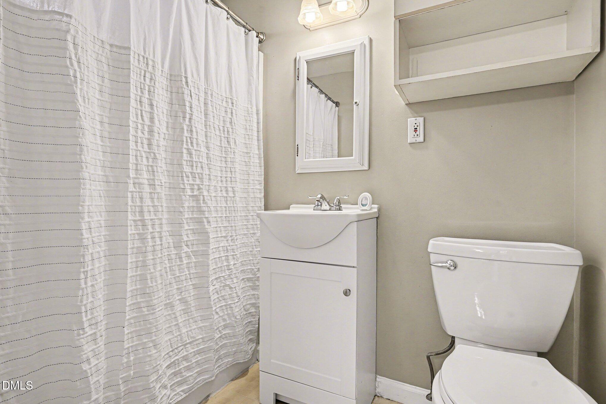 3400 Octavia Street Raleigh, NC 27606 - Photo 35 of 36 a white toilet sitting next to a white sink a shower curtain