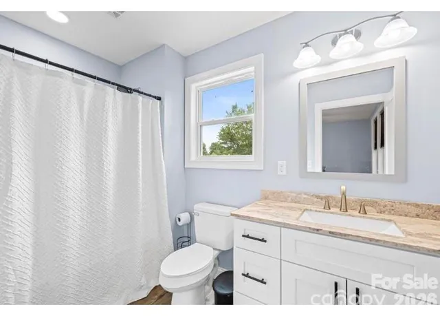 a bathroom with a granite countertop sink toilet and mirror