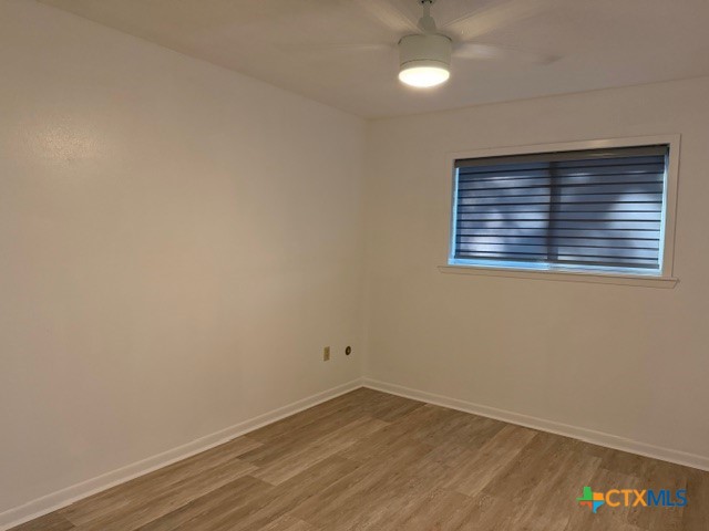 508 East Travis Street Luling, TX 78648 - Photo 11 of 17 an empty room with wooden floor and windows