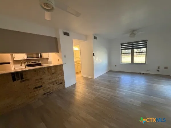 an empty room with wooden floor and windows