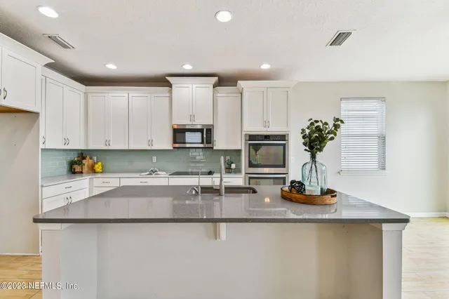 a kitchen with kitchen island granite countertop a sink a stove a counter space and cabinets