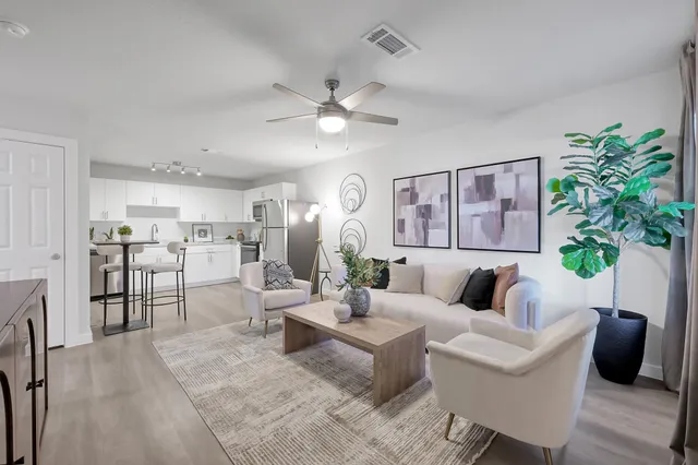 a living room with furniture potted plant and open kitchen view