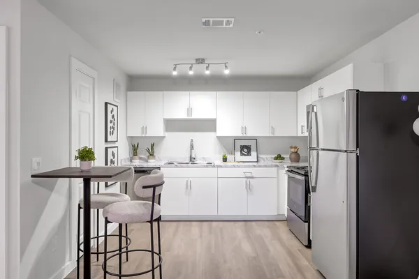 a kitchen with a refrigerator a sink dishwasher a stove and white cabinets with wooden floor