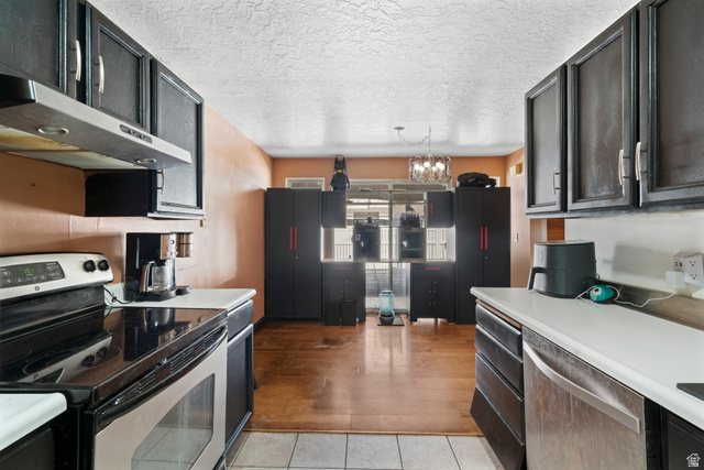 165 Pheasantbrook Drive Centerville, UT 84014 - Photo 7 of 30 Kitchen with stainless steel appliances, light countertops, a textured ceiling, suspended lighting, and dark cabinetry